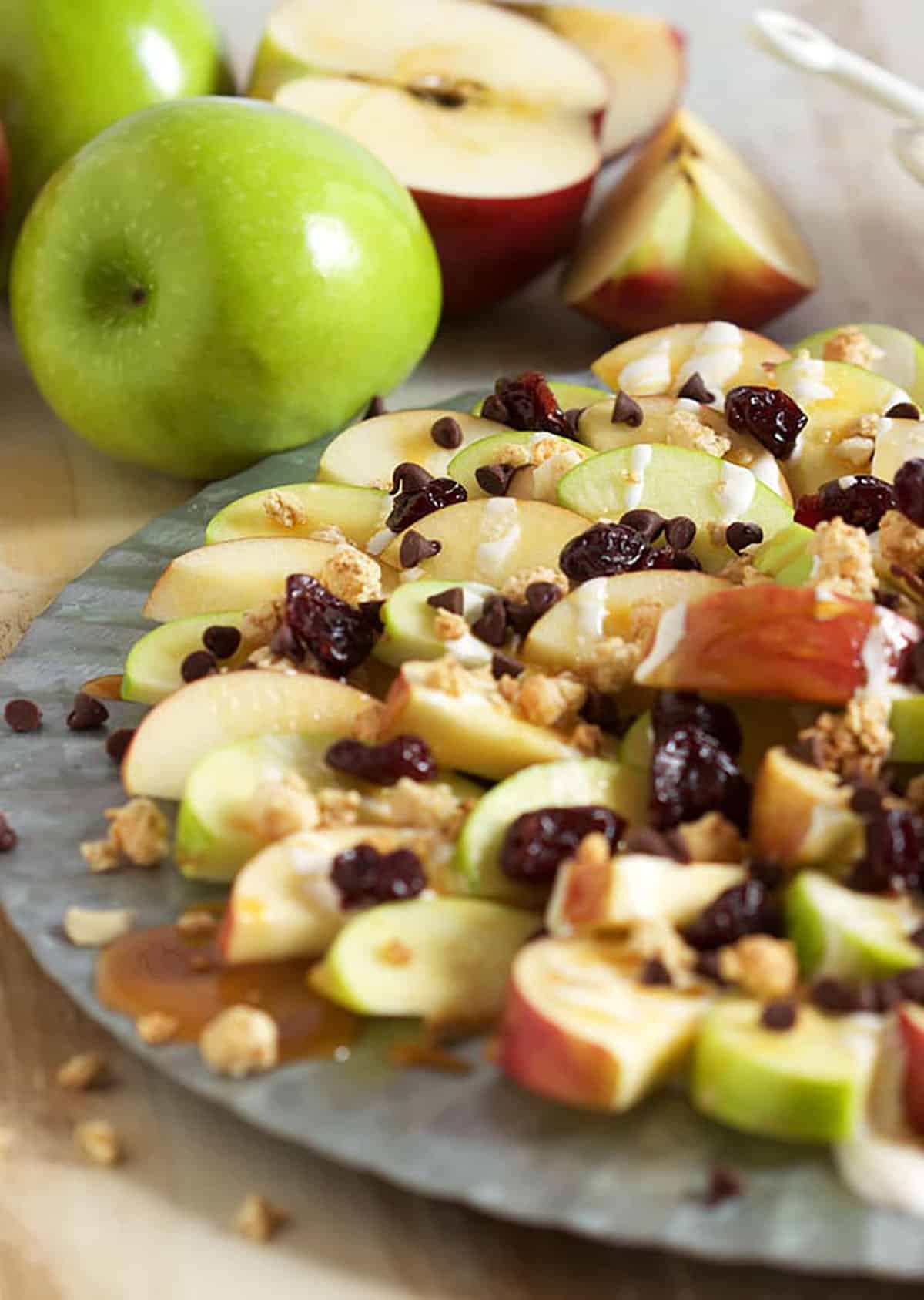 Caramel Apple Nachos on a platter with a green apple in the background.