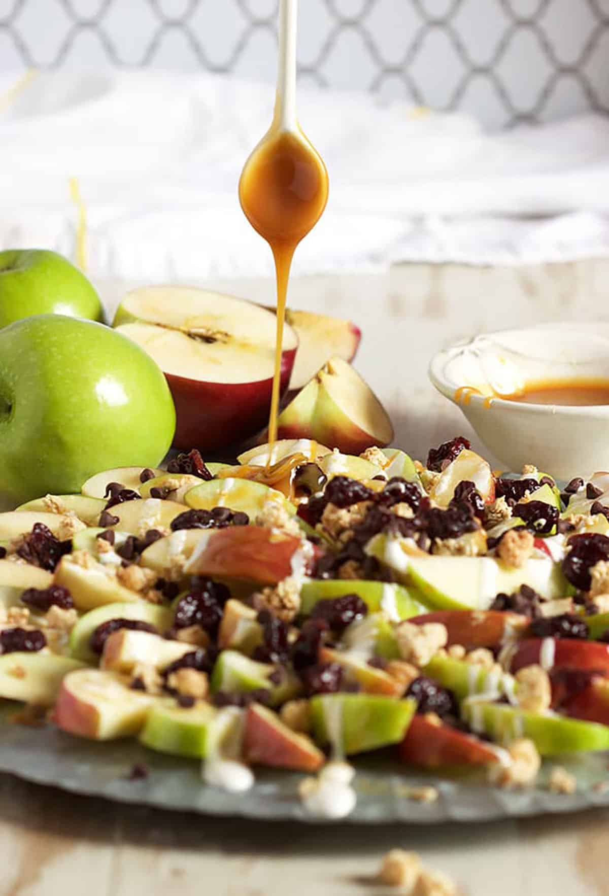 Caramel Apple Nachos on a platter with caramel being drizzled on top.