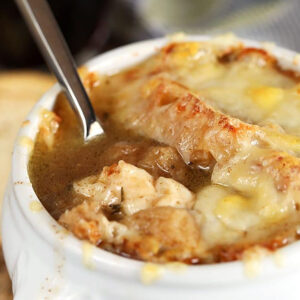 Close up of French onion soup with a spoon in it.