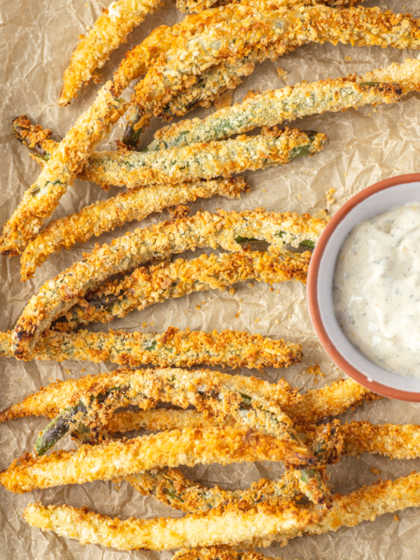 A serving of fried green beans are presented on beige surface.