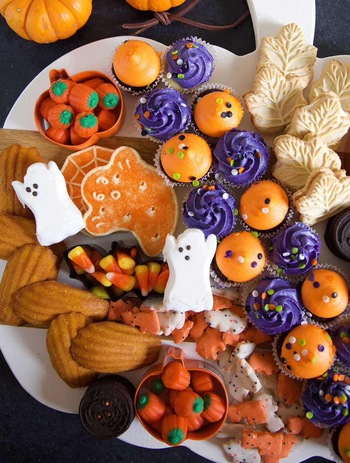 Ghost peeps, mini cupcakes, cookies and candies are presented on a white serving tray.