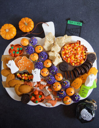 A white pumpkin sering platter is topped with an assortment of Halloween themed treats.