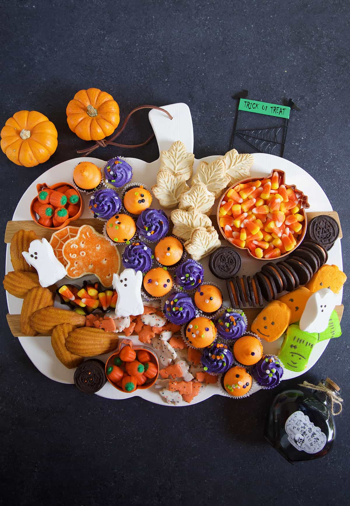 A white pumpkin sering platter is topped with an assortment of Halloween themed treats.