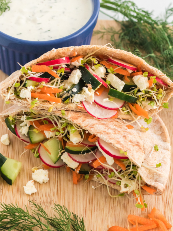 A sliced in half pita pocket is presented on a wooden cutting board.