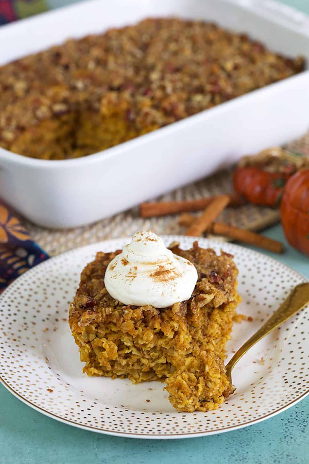 Pumpkin Baked Oatmeal slice on a white plate with a gold fork.
