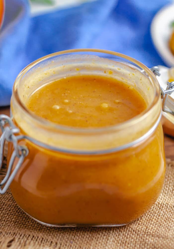A small glass jar is filled with caramel pumpkin sauce.
