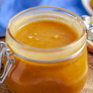 A small glass jar is filled with caramel pumpkin sauce.