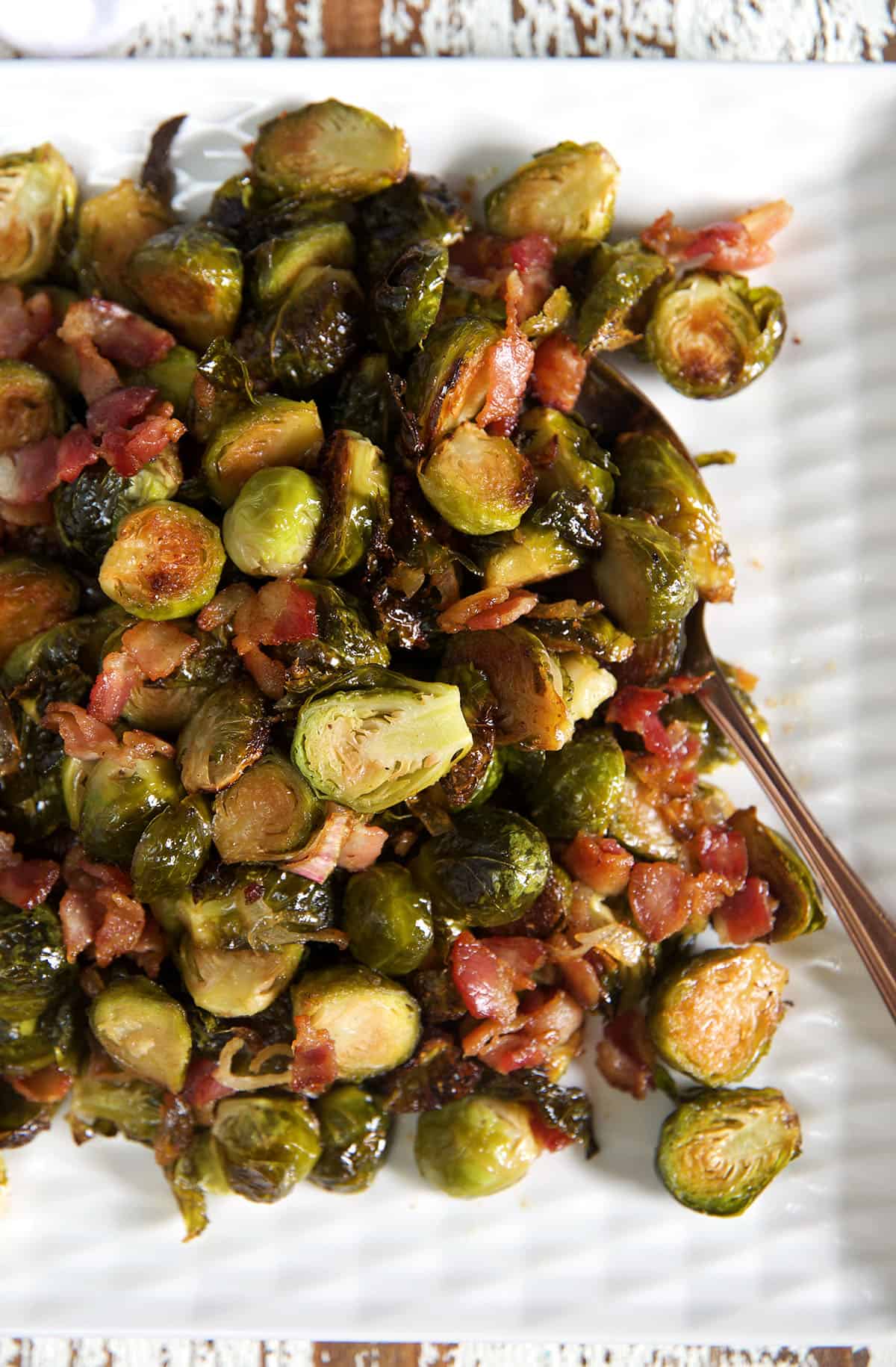 A serving spoon is placed next to a heaping portion of bacon brussel sprouts.