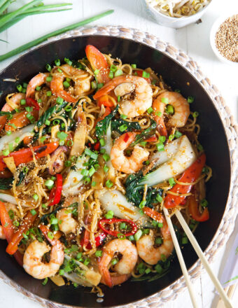 Chopsticks are placed in a skillet filled with shrimp chow mein.