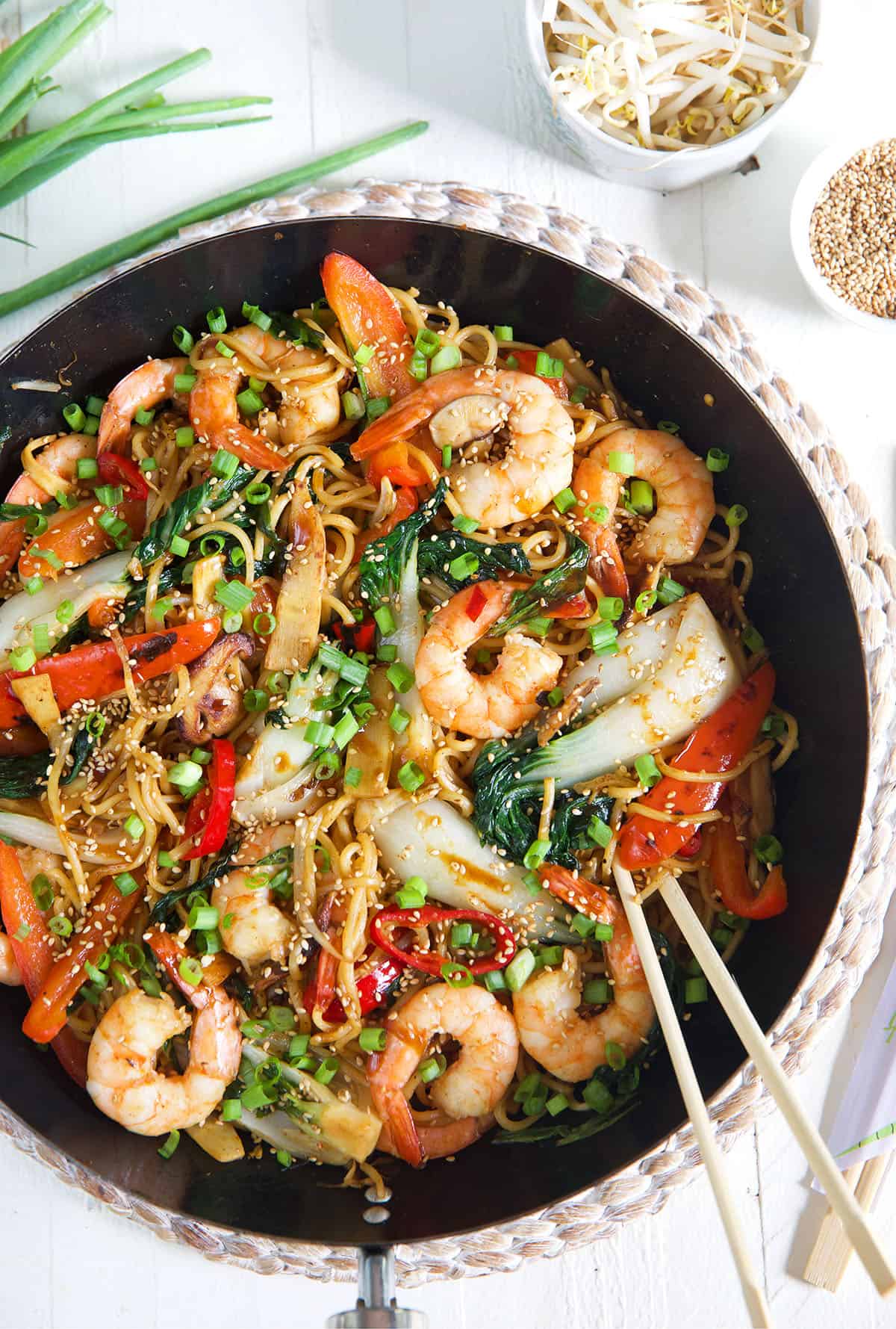 Chopsticks are placed in a skillet filled with shrimp chow mein.