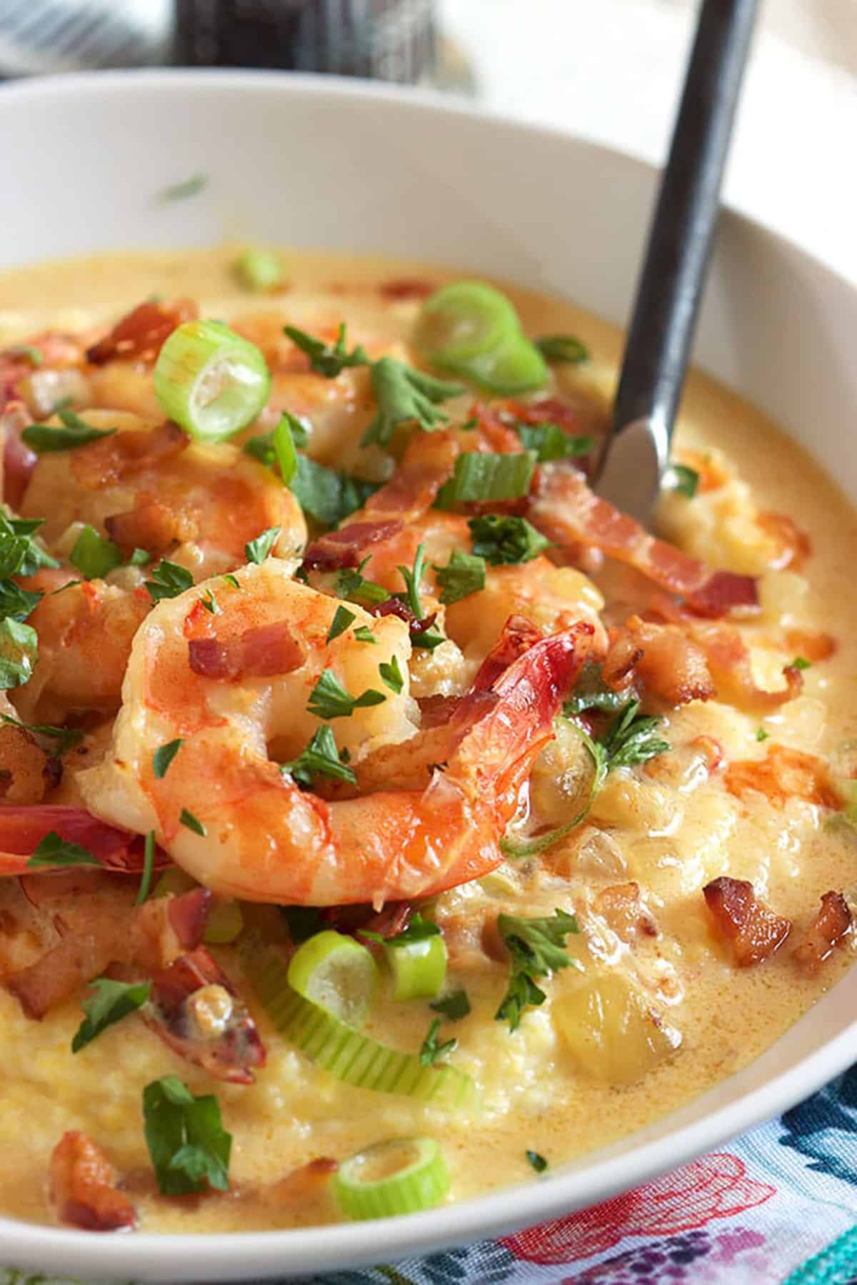 Shrimp and Grits in a white bowl with a black fork in the dish.