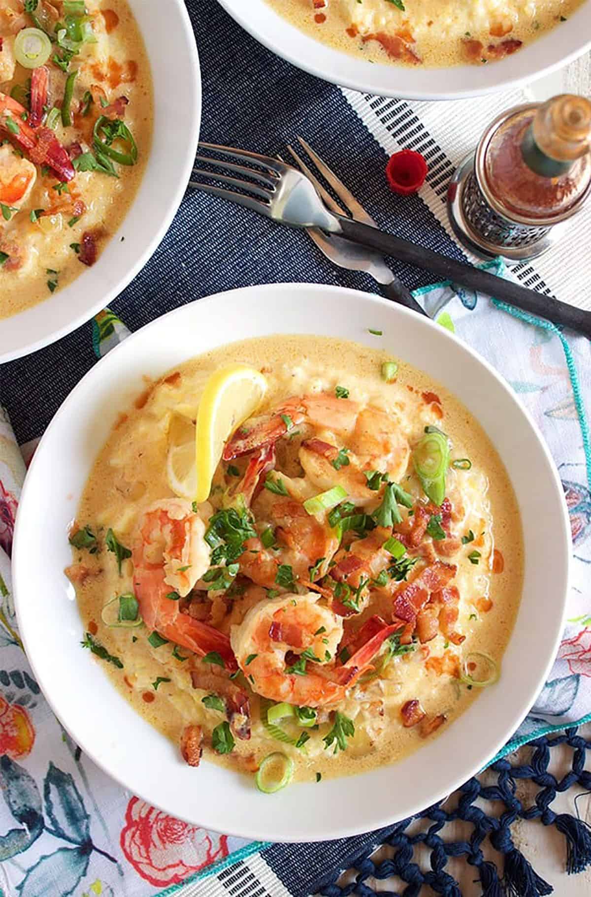 shrimp and grits in a white bowl on a blue and white place mat.