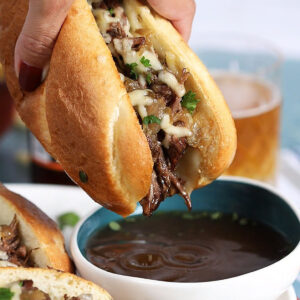French Dip Sandwich with a drop of au jus dripping back into a bowl of broth.