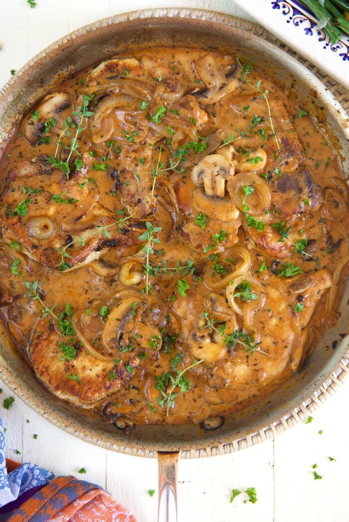 A skillet is filled with pork chops in brown gravy.
