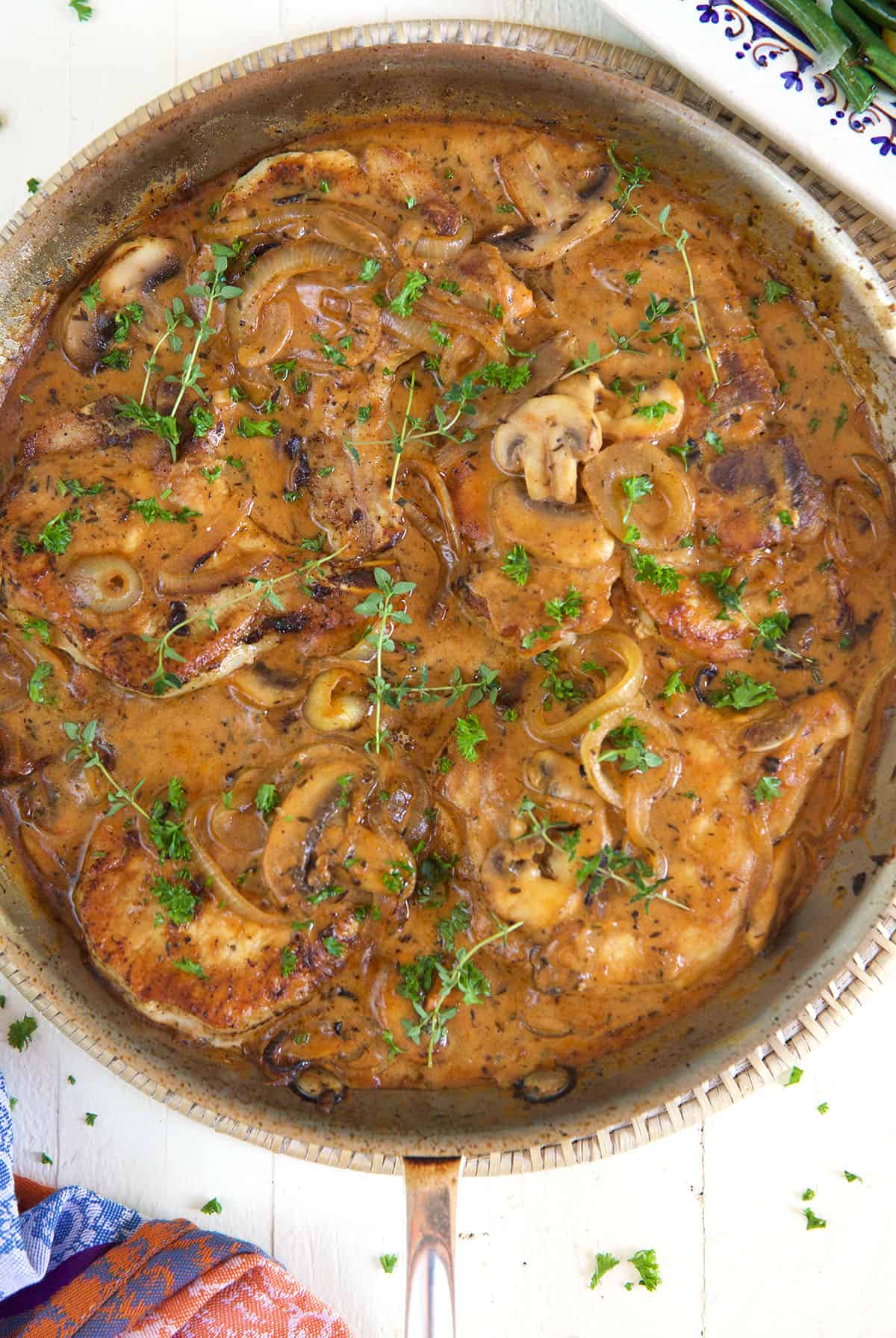 A skillet is filled with pork chops in brown gravy.