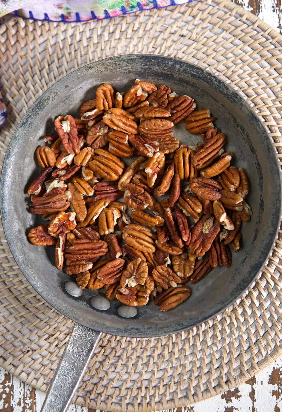 Pecans are toasted in a gray skillet.