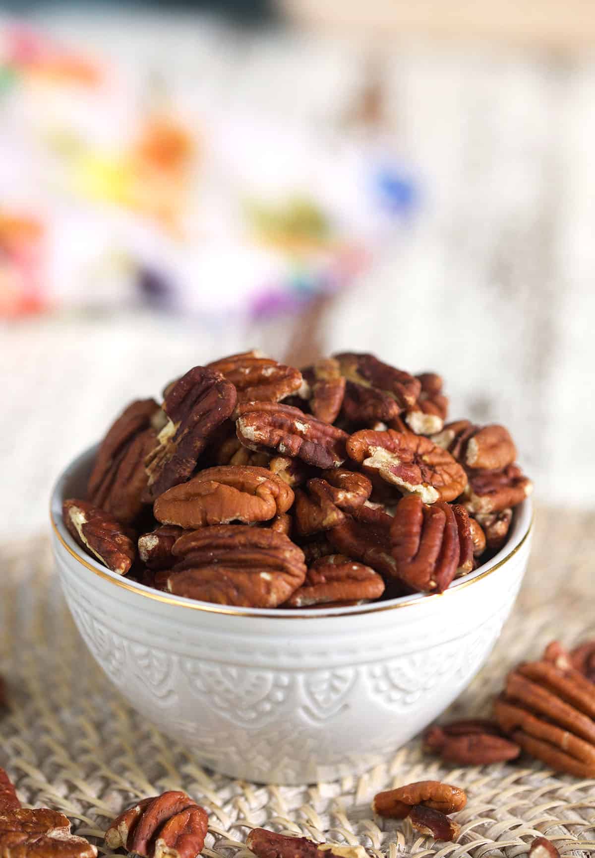 A small white bowl is filled to the brim with pecans. 
