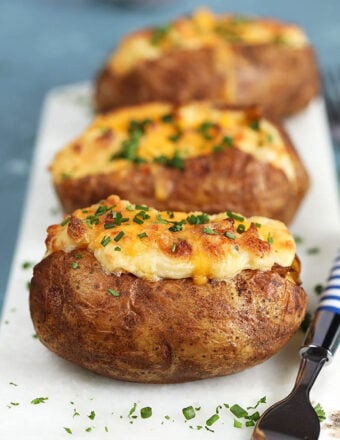 Twice Baked Potatoes with Cheddar and Chives on a white marble board.