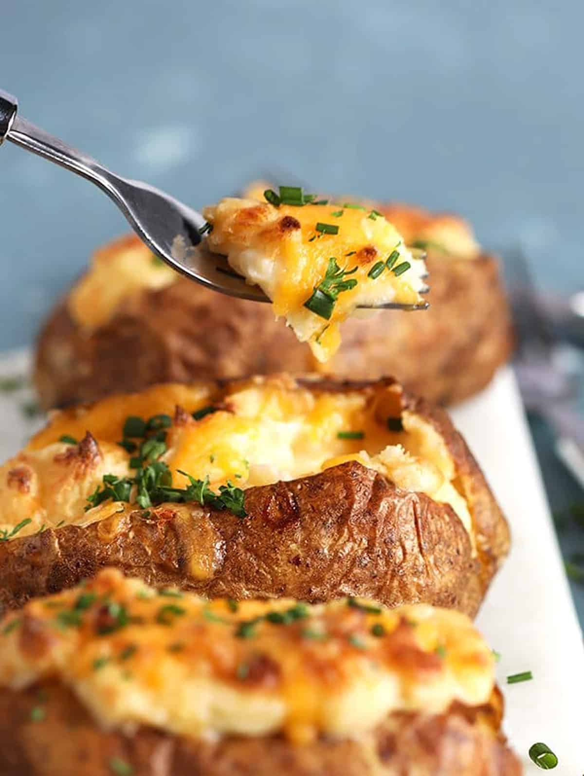 Close up of twice baked potatoes with a fork taking a bite.