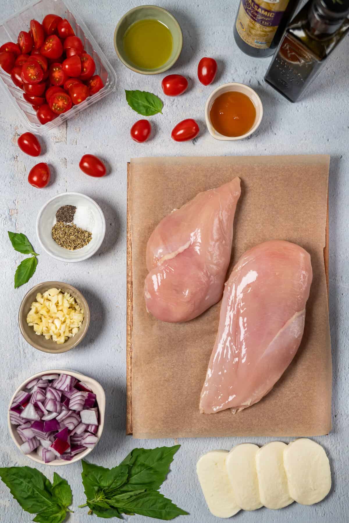The ingredients for chicken caprese are spread out on a white surface.