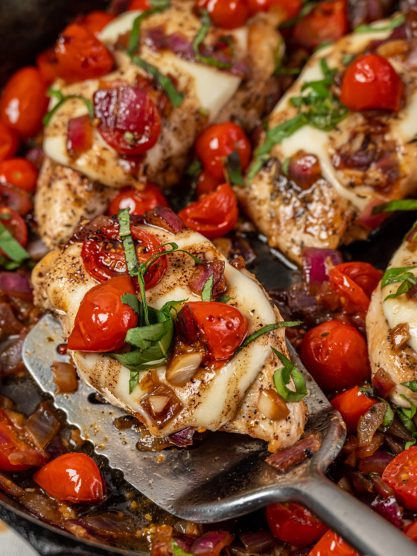 A piece of chicken is being lifted from the skillet with a spatula.