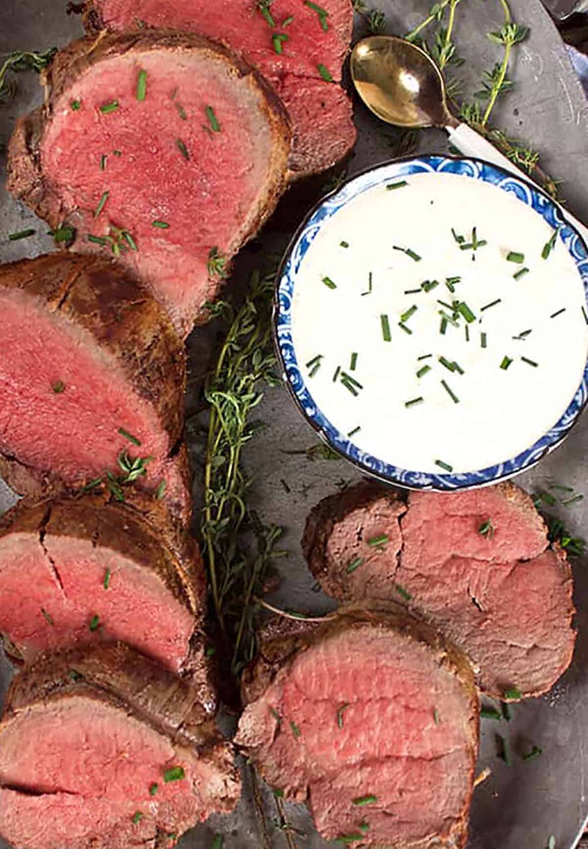 platter with sliced beef tenderloin and a bowl of horseradish sauce.