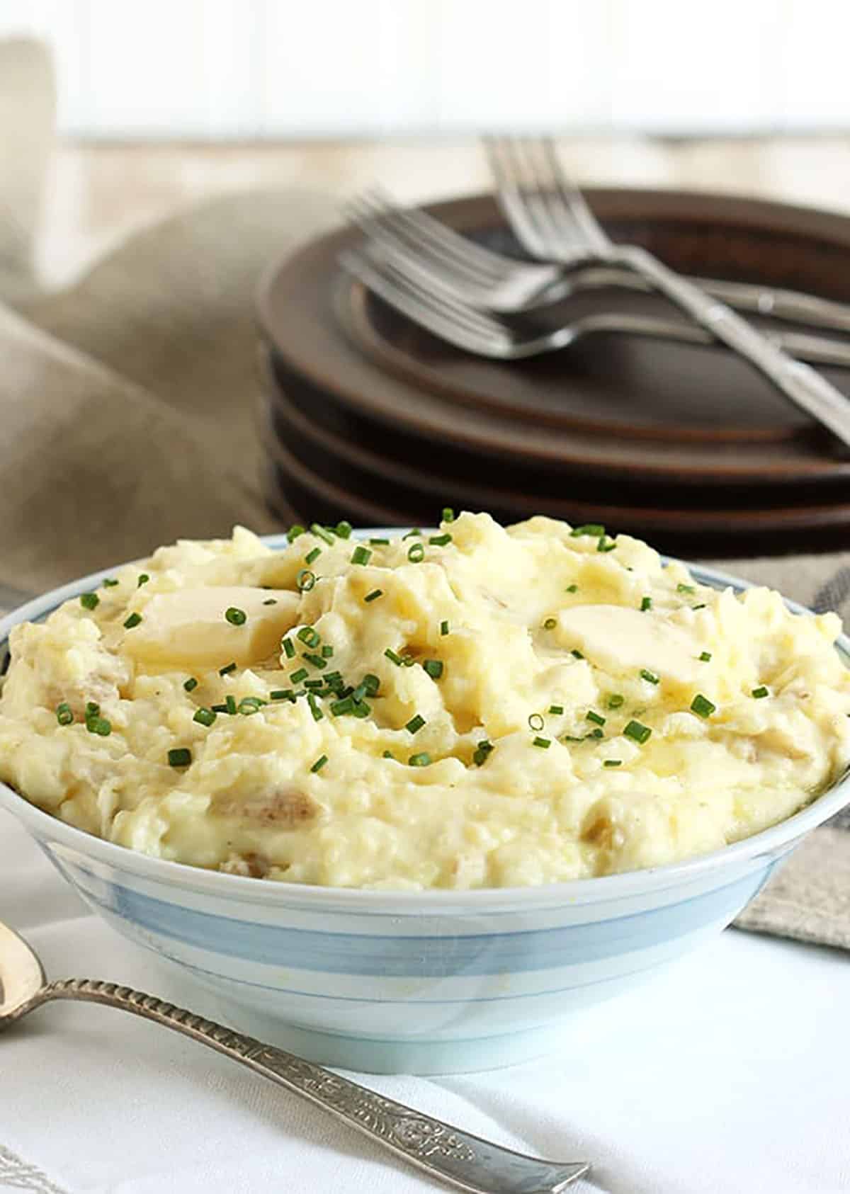 Mashed potatoes in a blue and white bowl with a silver spoon in the front.