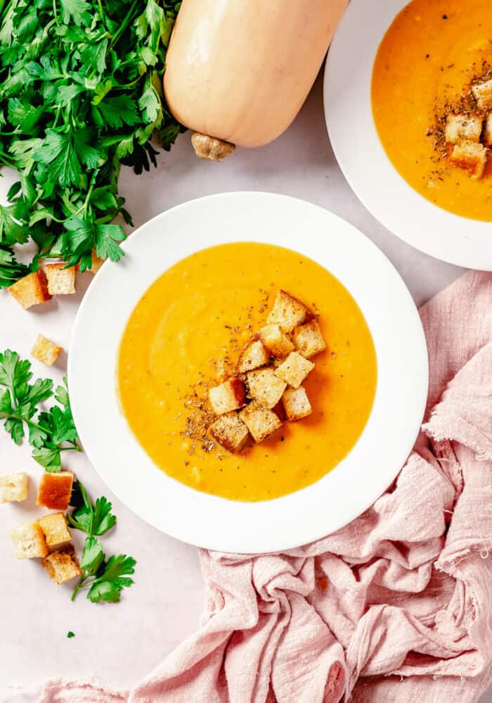 A bowl of sweet potato squash soup is topped with croutons.