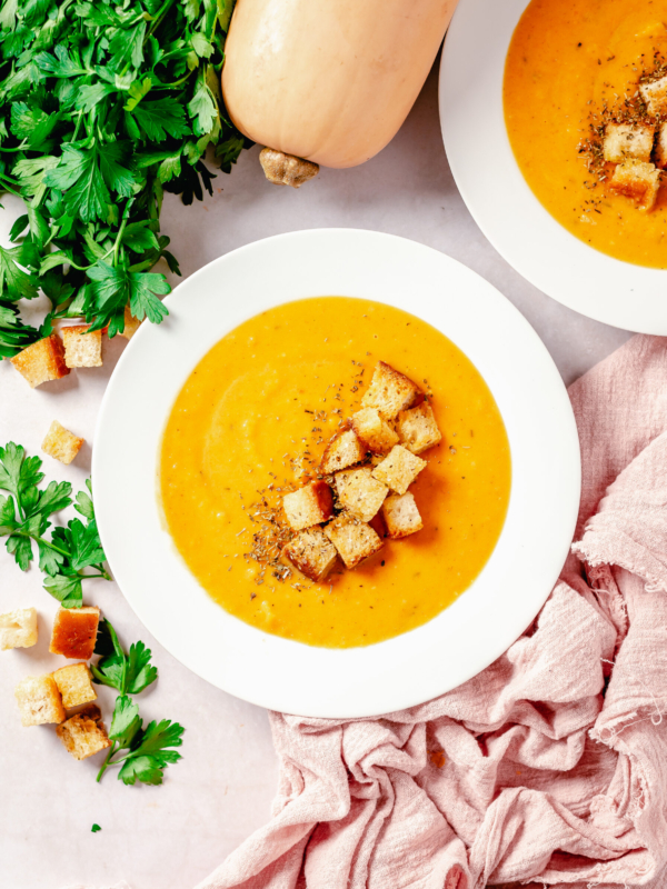 A bowl of sweet potato squash soup is topped with croutons.