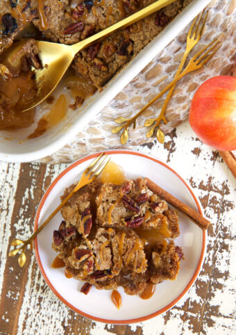 A serving of apple dump cake is presented on a white plate next to a dish filled with more cake.