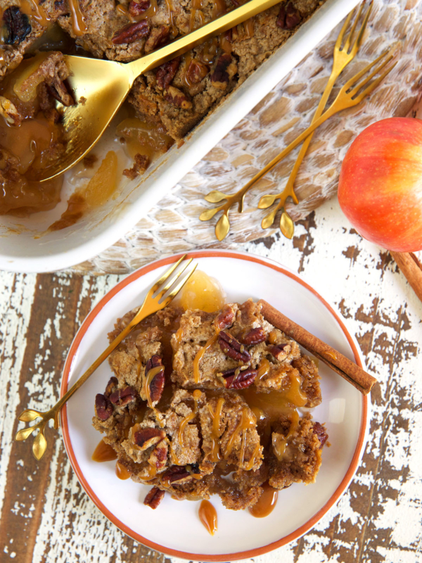 A serving of apple dump cake is presented on a white plate next to a dish filled with more cake.