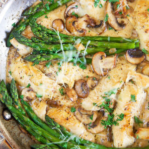Cheesecake Factory Chicken Madeira in a skillet with asparagus.