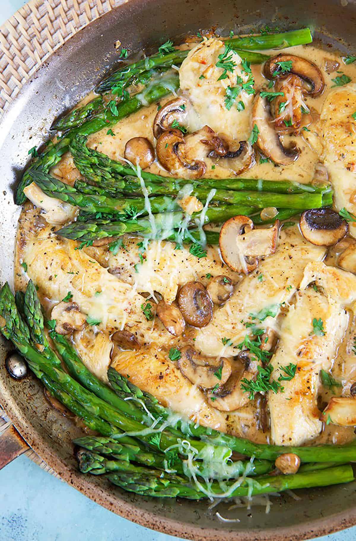 Cheesecake Factory Chicken Madeira in a skillet with asparagus.