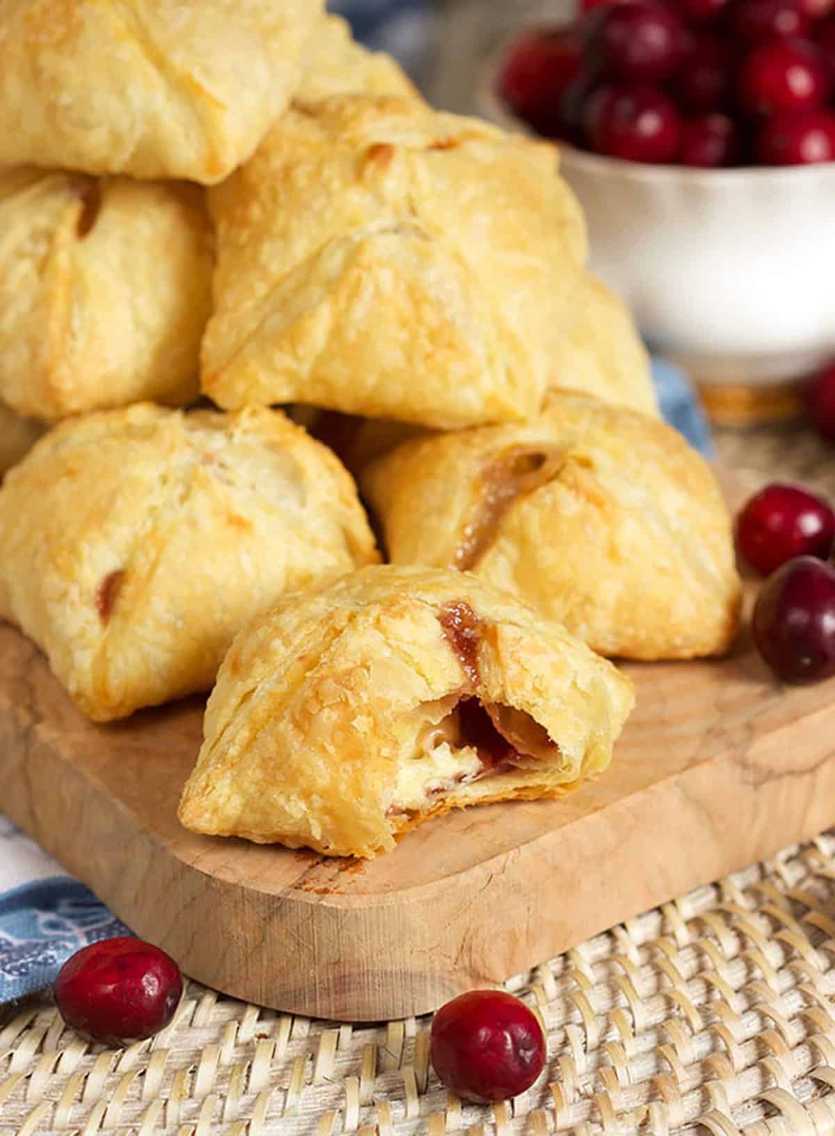 Cranberry Brie Bites Stacked on a board with one having a bite taken out of it.