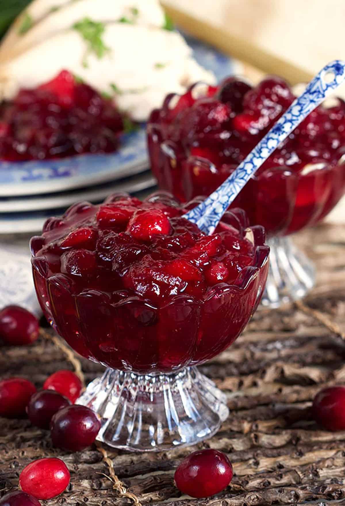 Cranberry sauce in a glass dessert bowl on a placemat made with twigs.