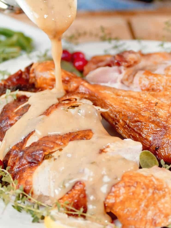 Gravy is being poured over roast turkey.