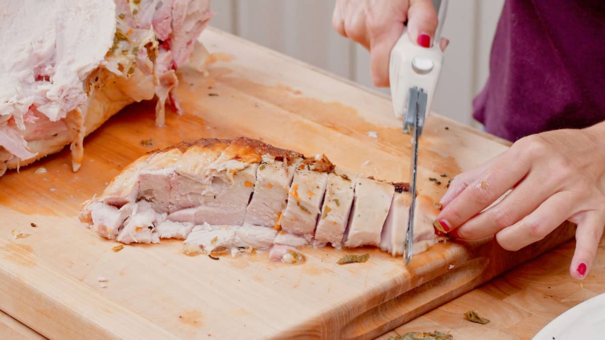Turkey breast being sliced on a cutting board.