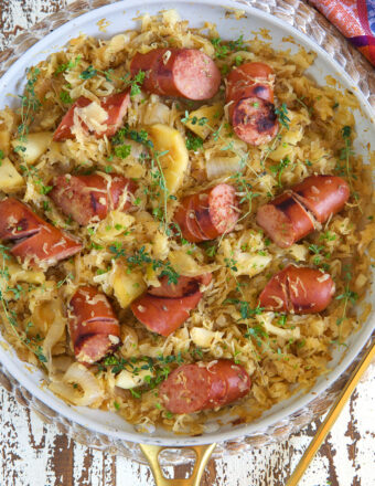 A large pan is filled with kielbasa and saurkraut.