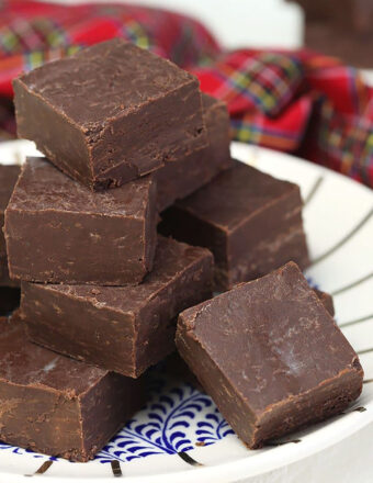 Pieces of fudge are on a white plate, ready to be eaten.
