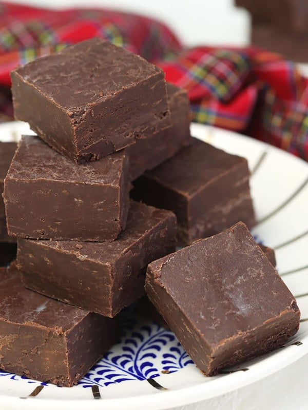 Pieces of fudge are on a white plate, ready to be eaten.