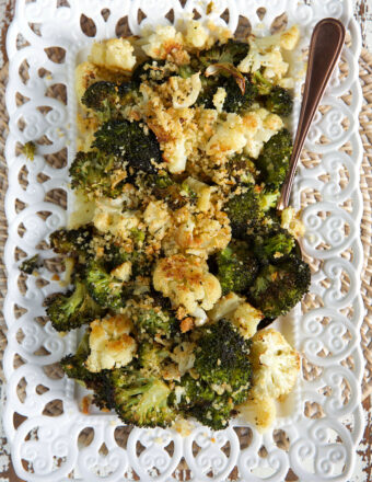A large portion of roasted broccoli and cauliflower is presented on a white serving tray.