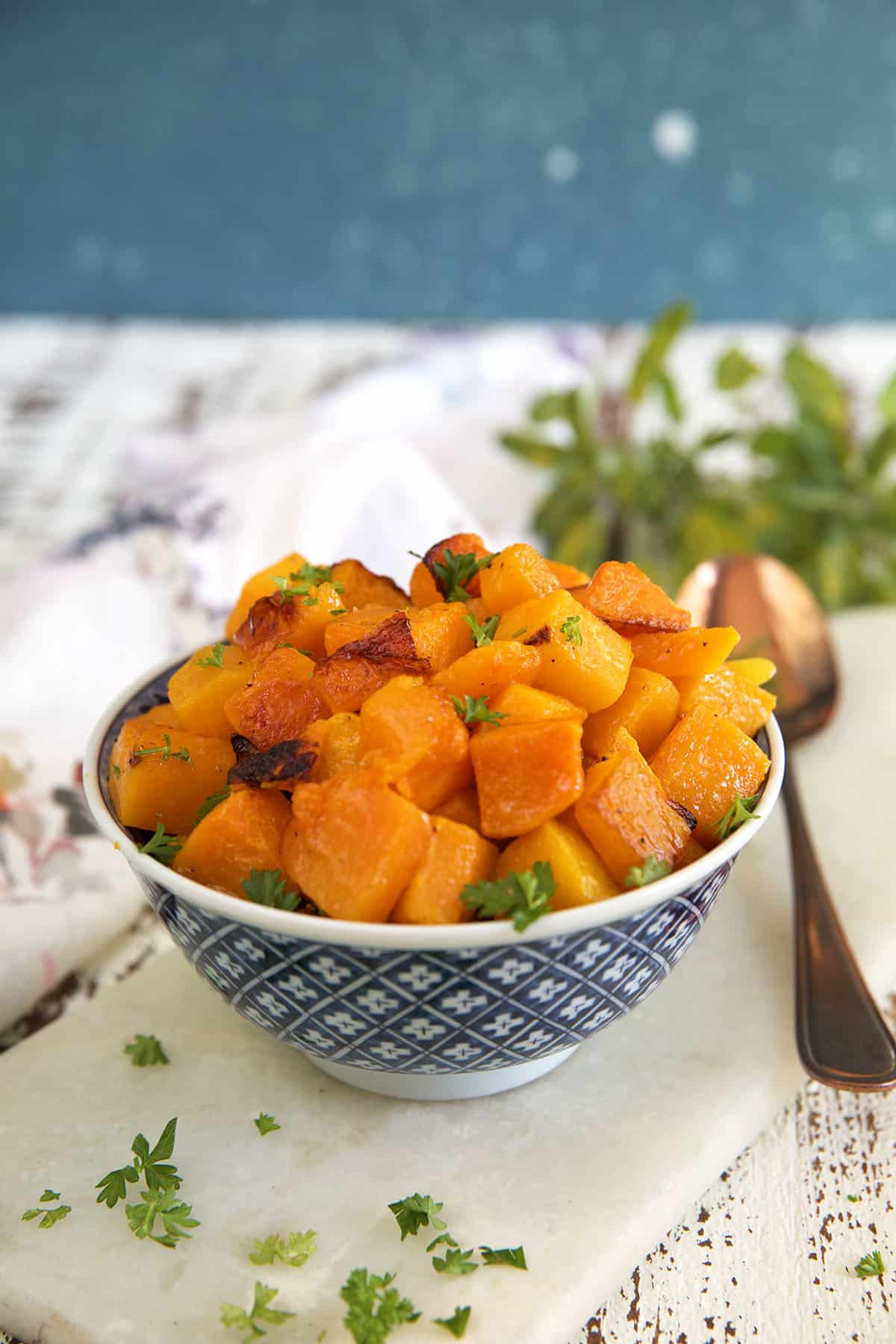 A blue and white bowl is filled with chunks of roasted butternut squash. 