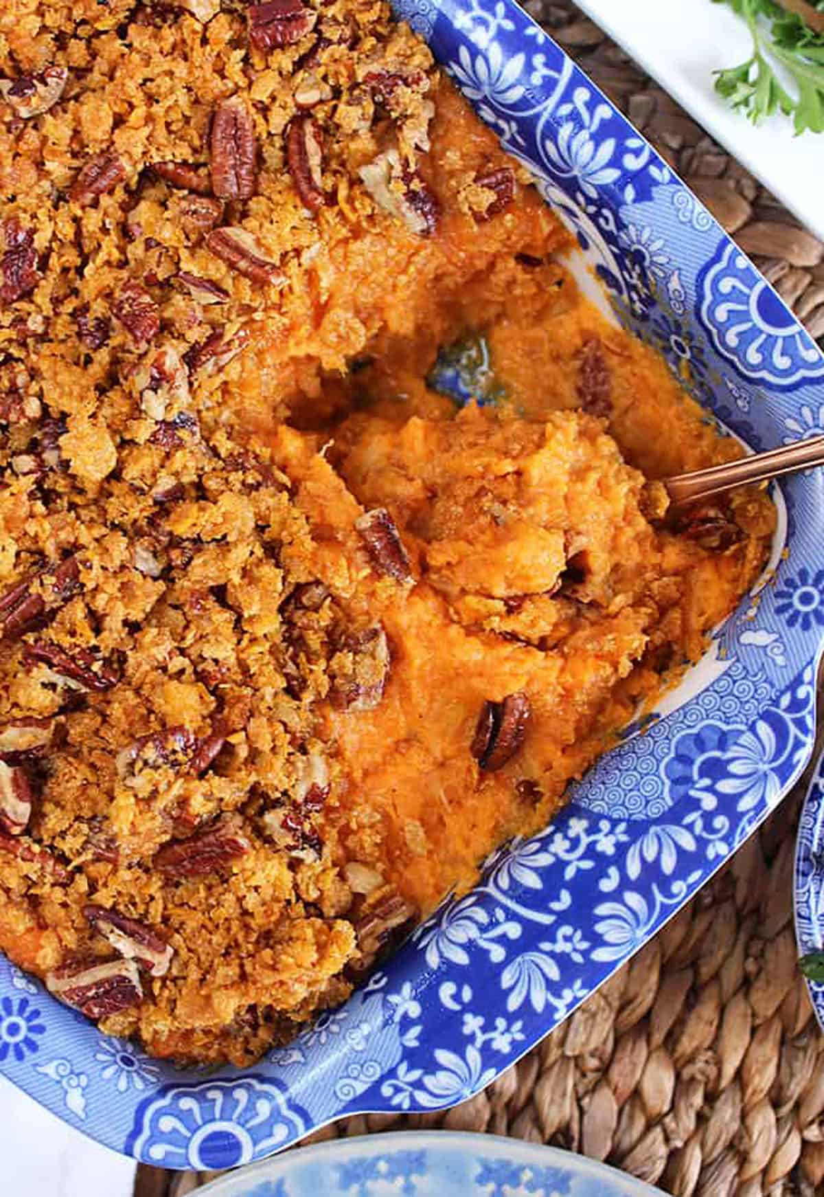 sweet potato casserole in a blue and white baking dish on a woven placemat.