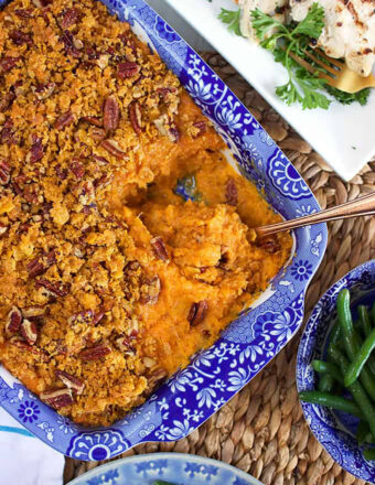 Sweet Potato Casserole in a blue and white baking dish with a serving spoon in it.
