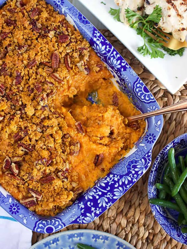Sweet Potato Casserole in a blue and white baking dish with a serving spoon in it.
