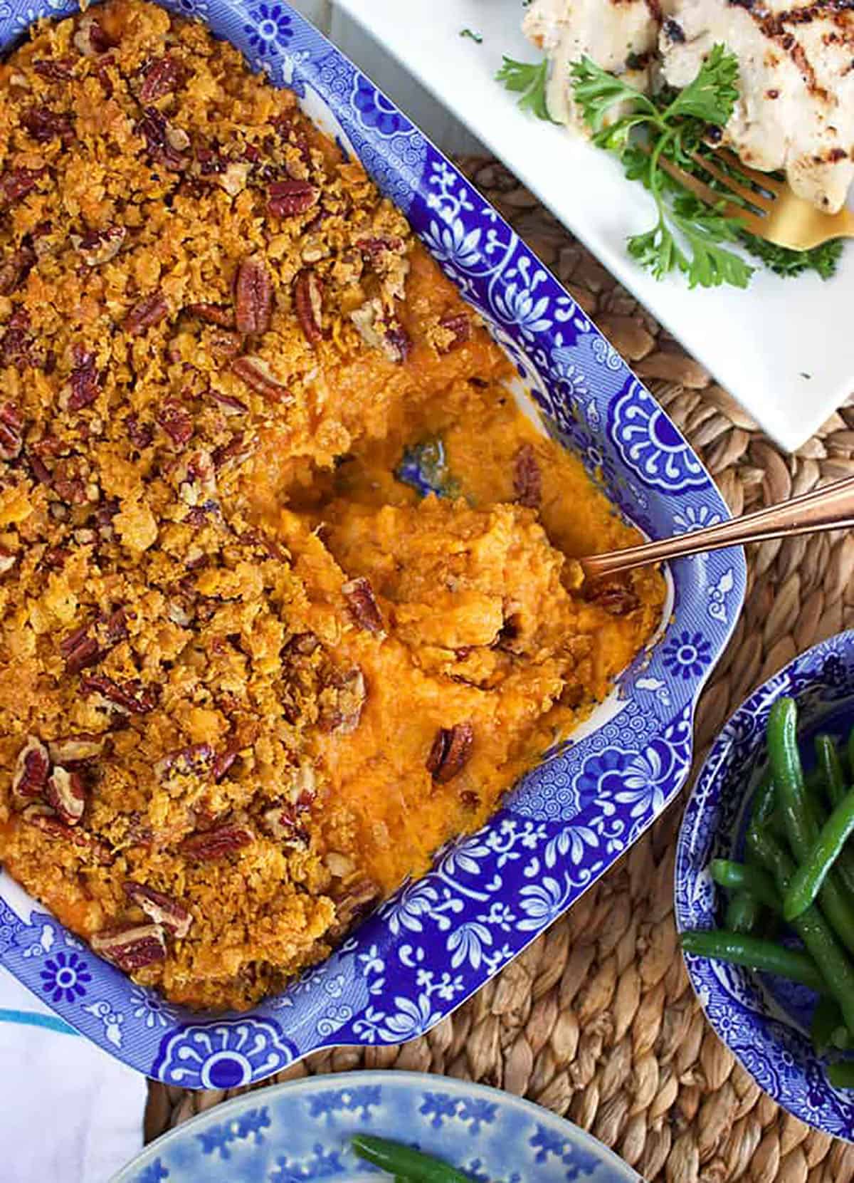 Sweet Potato Casserole in a blue and white baking dish with a serving spoon in it.