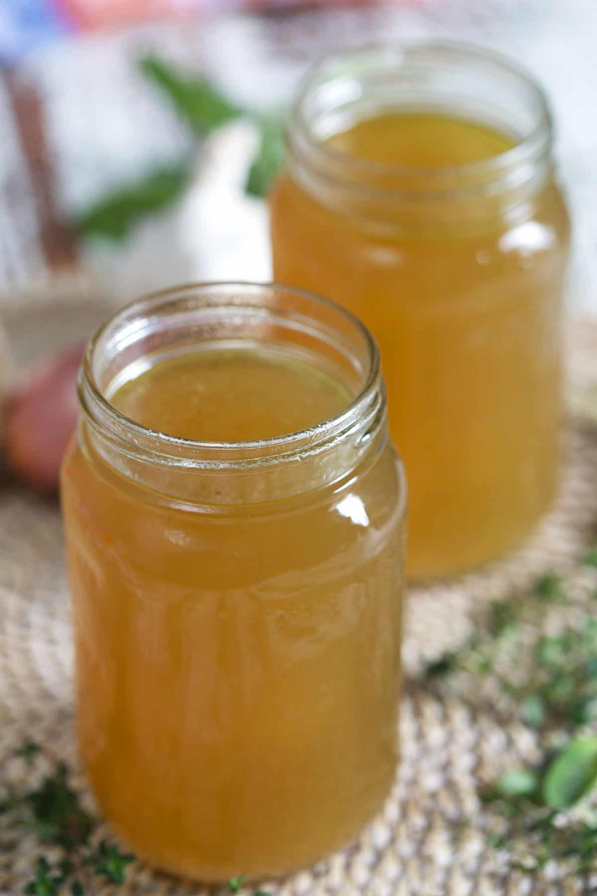 Two open glass jars are filled with turkey broth.