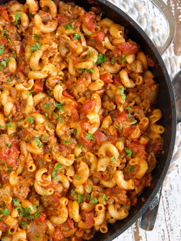 A large black skillet is filled with cooked goulash.