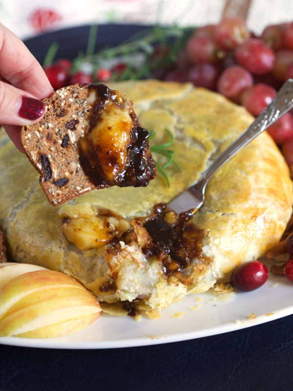 A small piece of bread is coated in brie and fig jam.