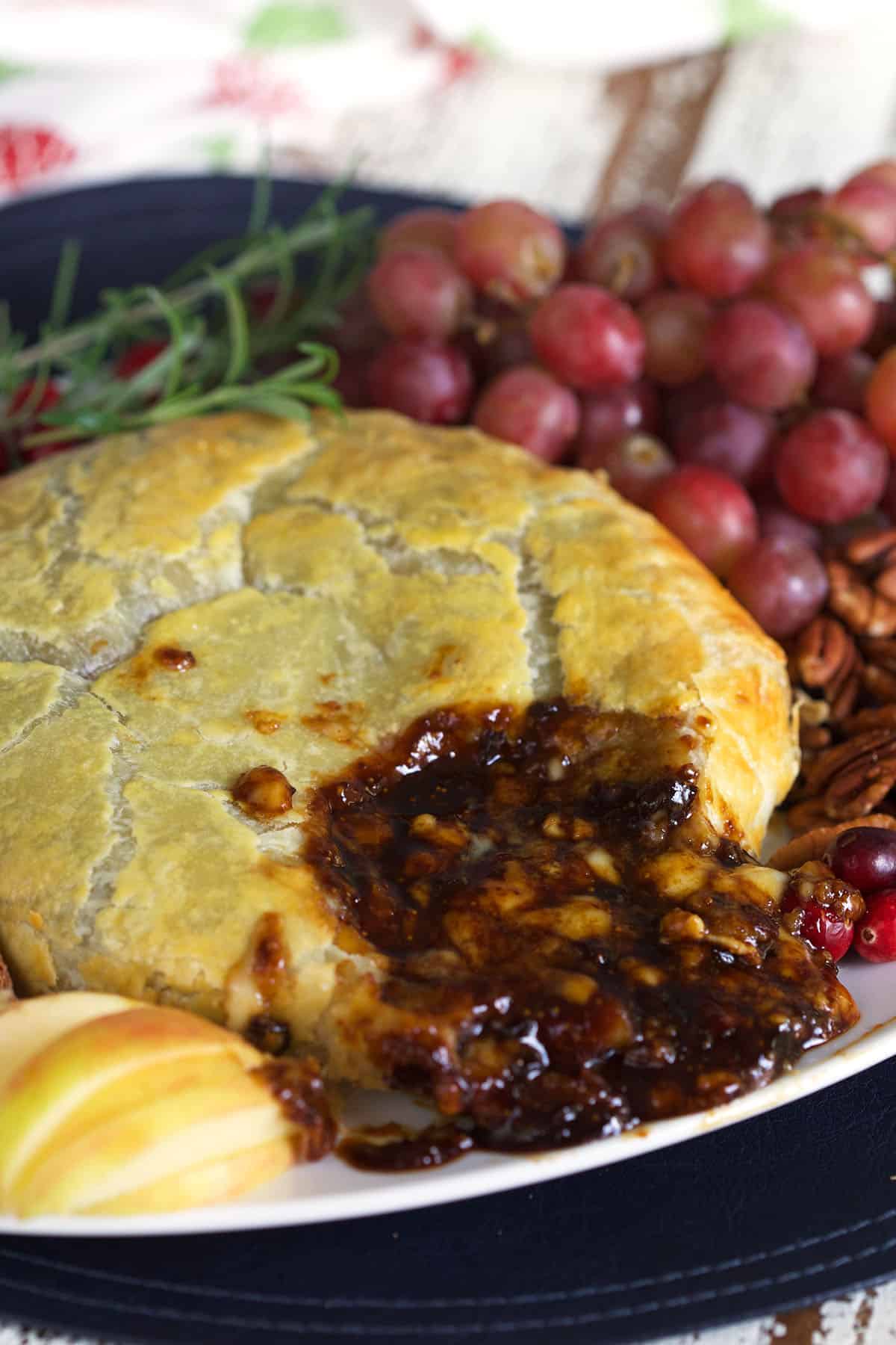 Fig jam is oozing out of a warm serving of baked brie.